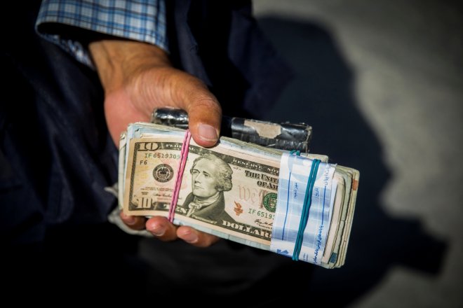 Money changer holds U.S. dollar bills at Grand Bazaar in the center of Tehran