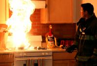 Firefighter demonstrates the incorrect method of putting out a stovetop fire with water.
