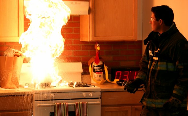 Firefighter demonstrates the incorrect method of putting out a stovetop fire with water.