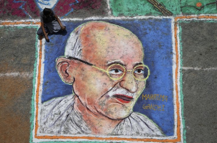 A student sits next to a painting of Mahatma Gandhi as part of Independence Day celebrations