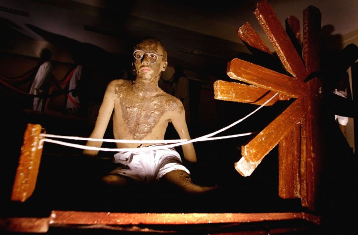 An Indian college student, smeared with clay to resemble Mahatma Gandhi, sits beside a spinning wheel during an event to mark the 55th anniversary of the death of Gandhi in Bombay January 30, 2003. Students from a city college reenacted several scenes fro