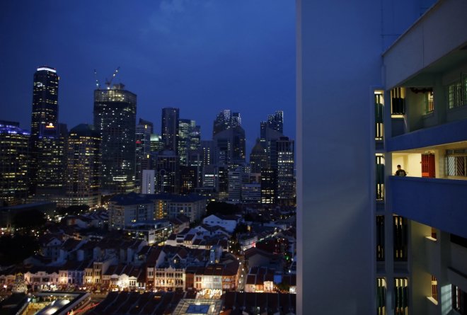 A man returns to his flat at the end of the work day at a Housing Development Board (HDB) public housing estate overlooking the financial district skyline in Singapore August 20, 2014. HDB apartments house around 80 percent of Singapore's 5.4 million peop