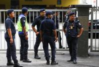 Malaysian police officers gather in front of the gate of the morgue at Kuala Lumpur General Hospital