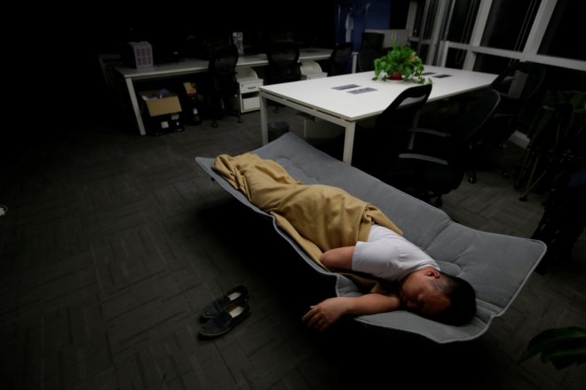 Ma Zhenguo, a system engineer at RenRen Credit Management Co., sleeps on a camp bed at the office after finishing work early morning, in Beijing, China, April 27, 2016. Office workers sleeping on the job is a common sight in China, where a surplus of chea Ma Zhenguo, a system engineer at RenRen Credit Management Co., sleeps on a camp bed at the office after finishing work early morning, in Beijing, China, April 27, 2016. Office workers sleeping on the job is a common sight in China, where a surplus of chea