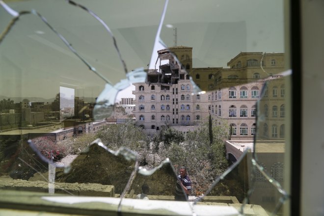 Damage in the building of the Houthi movement's politburo is seen through a broken window of an adjacent building