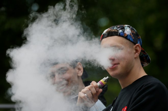Man exhales e-cigarette vapour in park in Kiev