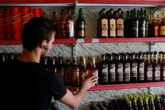 A liquor store owner checks bottles of alcohol at his store in the town of Qaraqosh