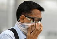 A man covers his face as he walks to work in Delhi