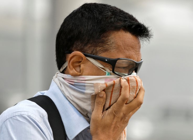A man covers his face as he walks to work in Delhi