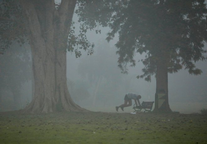 A man exercises in a park on a smoggy morning in New Delhi. A man exercises in a park on a smoggy morning in New Delhi.