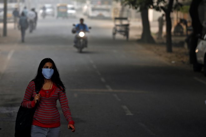 A woman walks along the road on a smoggy morning in Delhi.