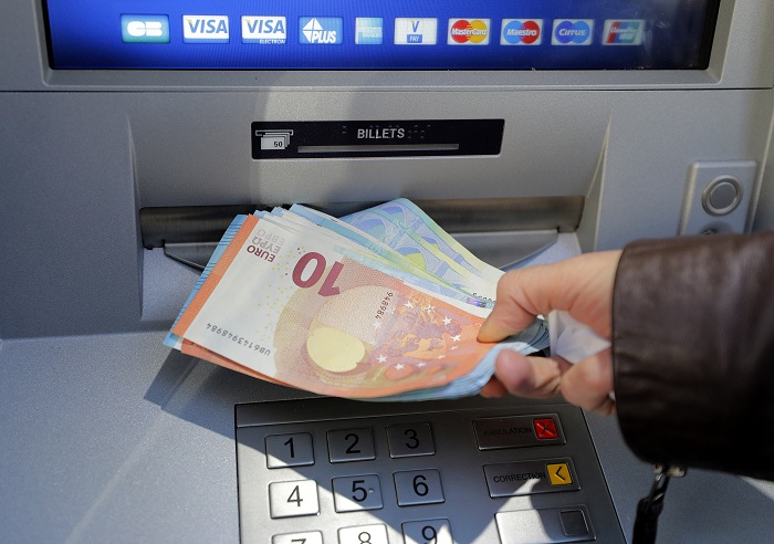 A woman withdraws money from an ATM machine in Nice