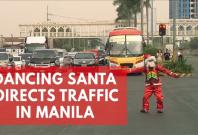 Dancing Filipino traffic cop in Santa Claus costume directs traffic in Manila