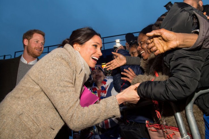 Britain's Prince Harry and his fiancee Meghan Markle greet well wishers as they leave after visiting