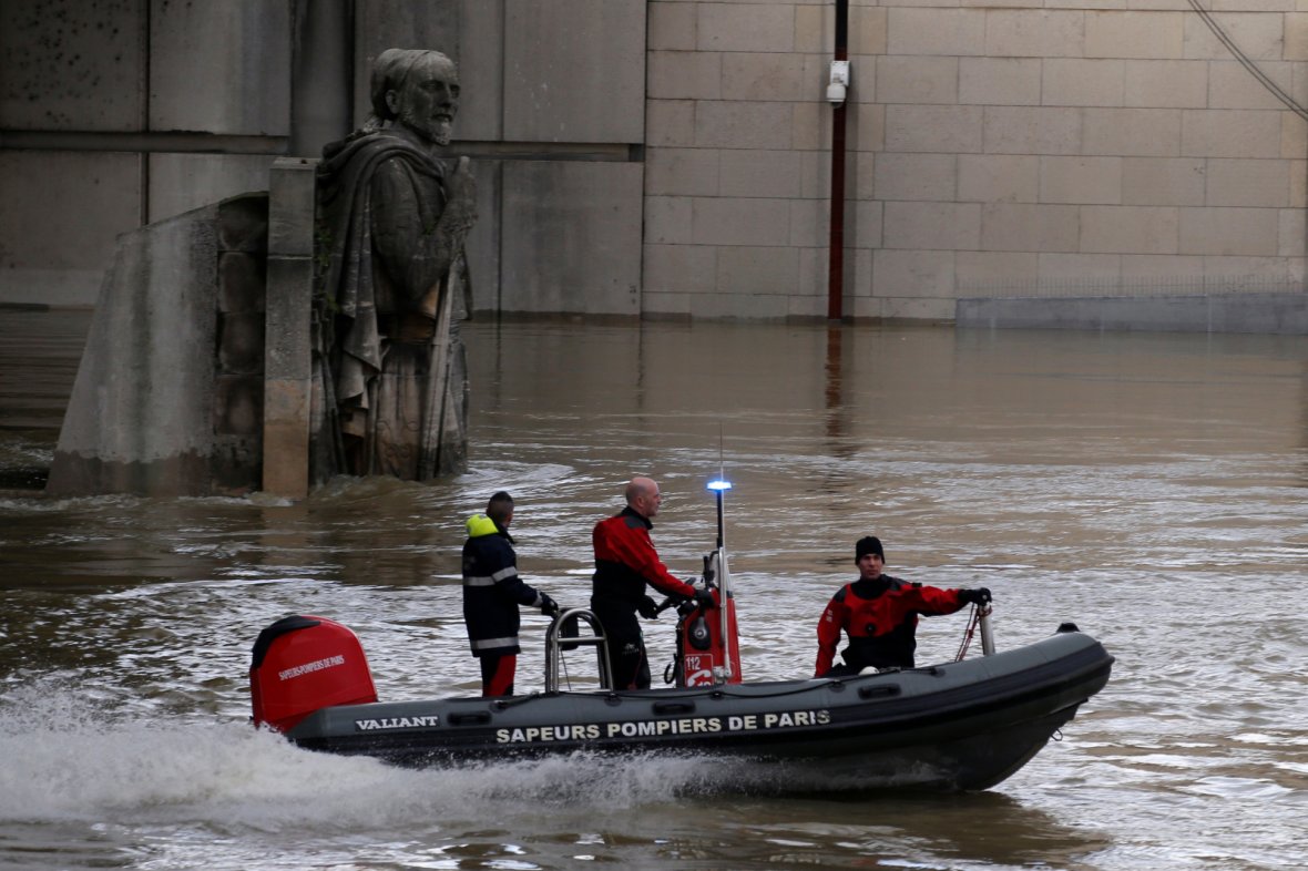 Paris fire brigade navigate a small craft past the Zouave soldier statue under the Pont d'Alma