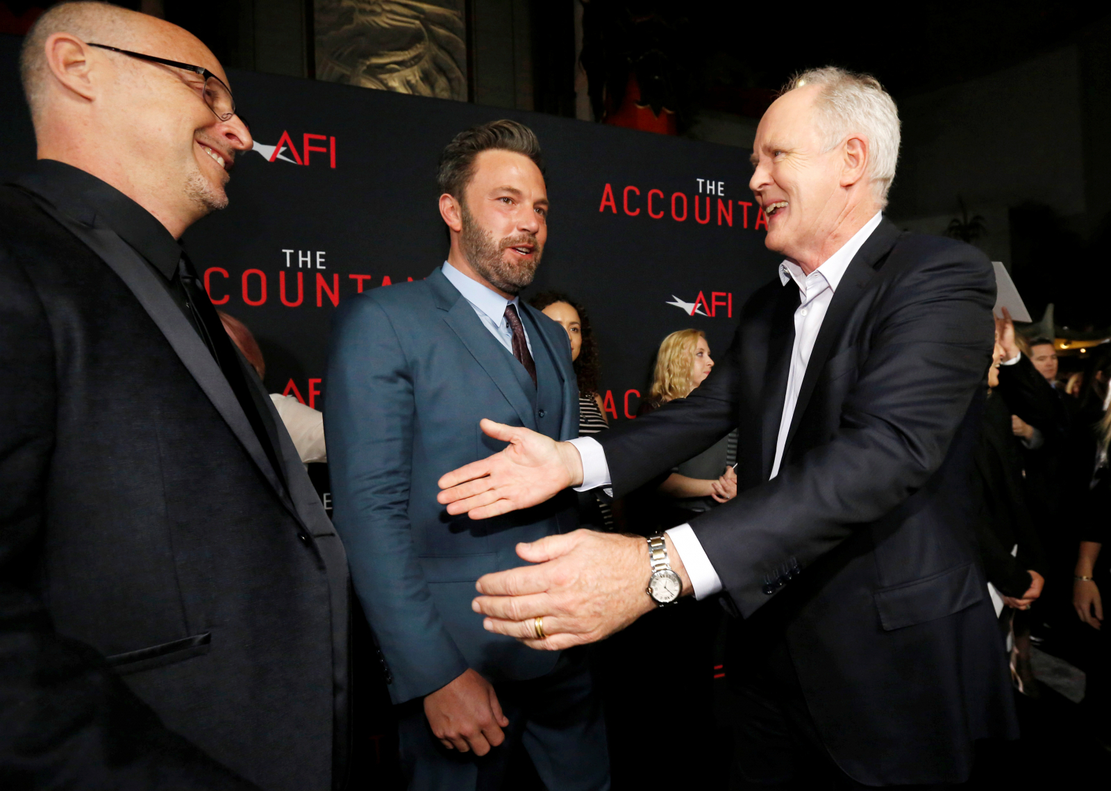 Director O'Connor greets cast members Affleck and Lithgow at the premiere of "The Accountant" 