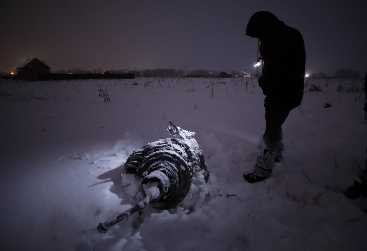 A man stands near a part of a Saratov Airlines Antonov AN-148 plane that crashed after taking off from Moscow's Domodedovo airport, outside Moscow