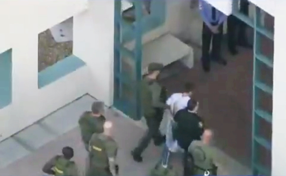 Police escort a suspect into the Broward Jail after checking him at the hospital following a shooting