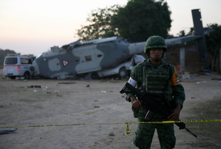 A soldier stands guard next to a military helicopter