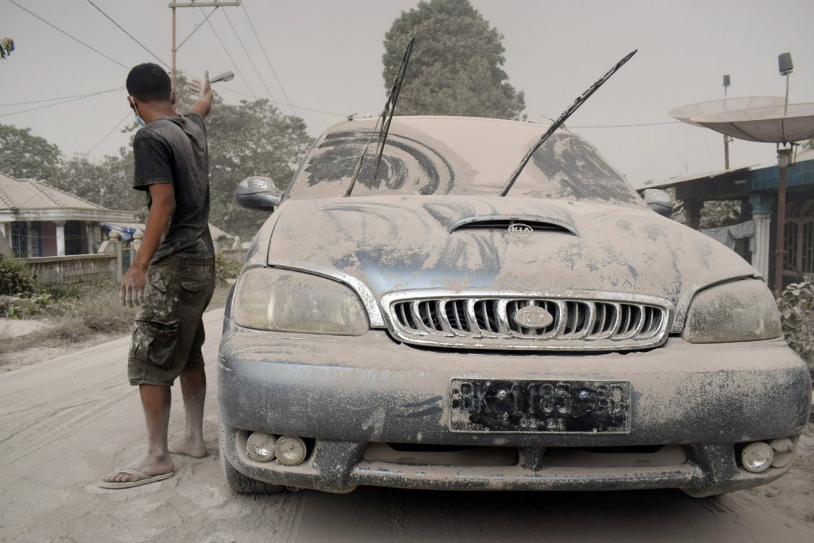 Ash from Mount Sinabung volcano covers a car and street following an eruption in Karo