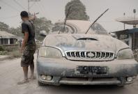 Ash from Mount Sinabung volcano covers a car and street following an eruption in Karo