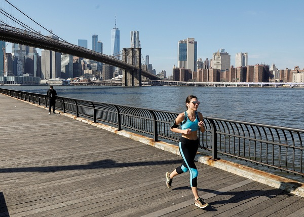 A woman runs along the East River through Brooklyn Bridge Park during unseasonably warm weather in Brooklyn, New York A woman runs along the East River through Brooklyn Bridge Park during unseasonably warm weather in Brooklyn, New York