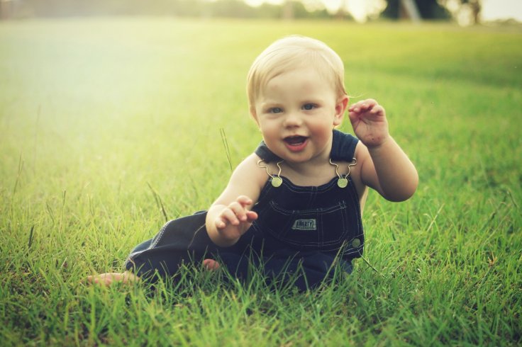 Infant sitting on the grassy ground 