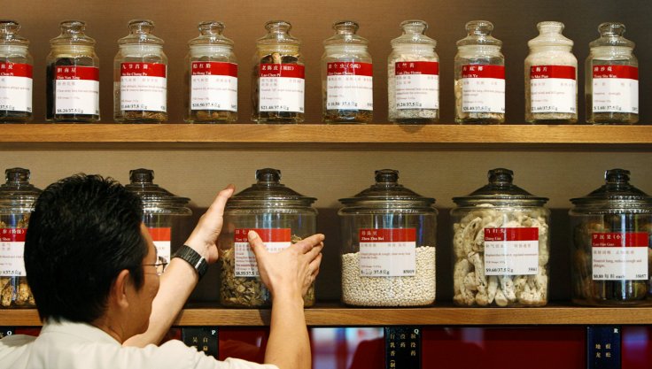 A shop assistant arranges jars containing roots and herbs at a Chinese medicine shop in Singapore