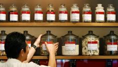 A shop assistant arranges jars containing roots and herbs at a Chinese medicine shop in Singapore