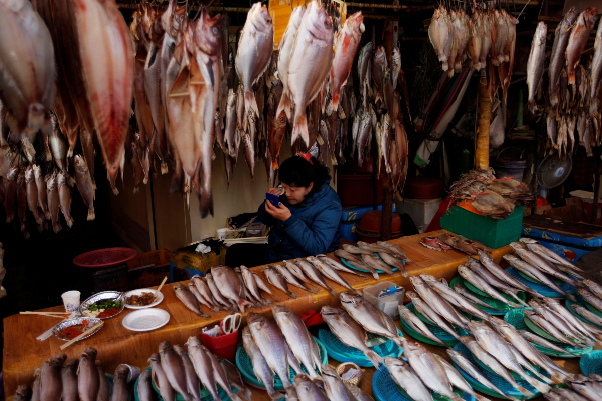 A storekeeper puts on her make-up at her store in Jagalchi Market in Busan