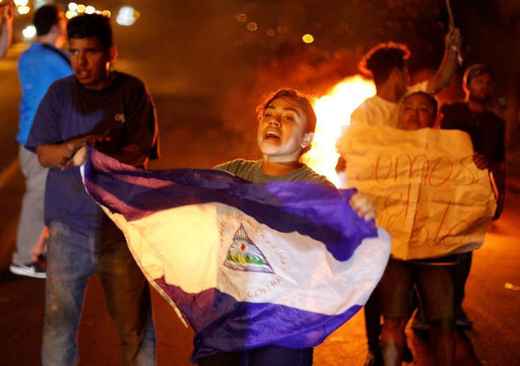 A demonstrator holds up a Nicaragua flag next to a burning barricade as demonstrators take part in a protest over a controversial reform to the pension plans of the Nicaraguan Social Security Institute (INSS) in Managua, Nicaragua April 21, 2018.