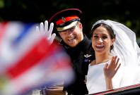 Britain’s Prince Harry and his wife Meghan wave as they ride a horse-drawn carriage after their wedding ceremony at St George’s Chapel in Windsor Castle in Windsor,
