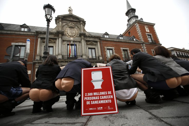 Activists from ONGAWA, Engineering for Human Development, pretend to defecate in front of Spain's foreign ministry, in Madrid, November 18, 2014.