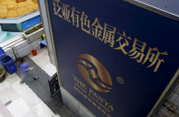 A woman walks past the company logo of the closed exchange centre of the Fanya Metal Exchange in downtown Kunming, Yunnan province, China, September 22, 2015. 