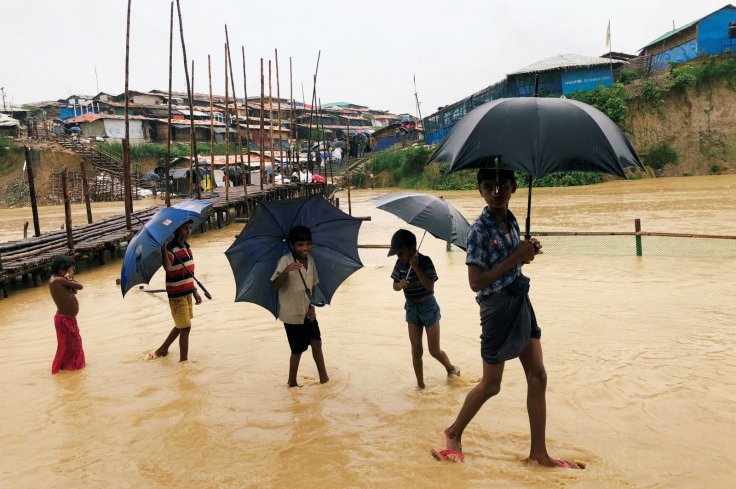 Rohingya refugee children walk along the water as parts of the Kutupalong camp flooded during heavy rain in Cox's Bazar, Bangladesh, July 4, 2018
