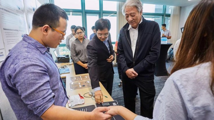 NUS Engineering Assoc Prof Jerald Yoo (second from right) demonstrating the Body Area Network project which aims to provide data and power connectivity through the human body to wearables, to Mr Teo