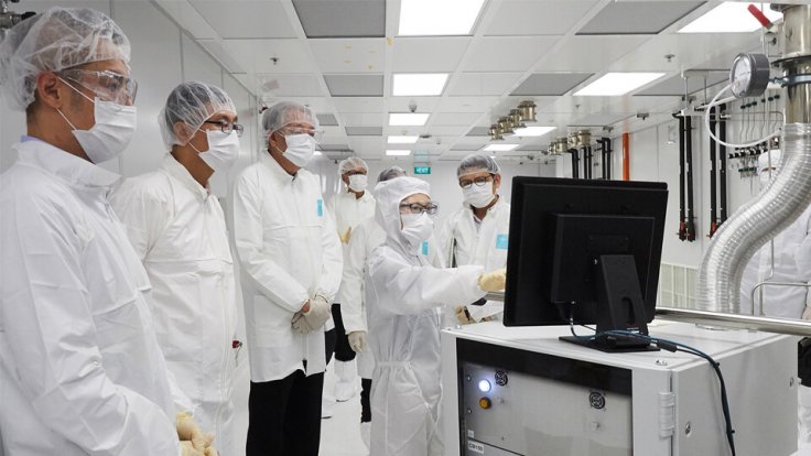 Mr Teo (third from left), together with Prof Tan (second from left) and Prof Chen (far left) in a cleanroom looking at data on a screen as a researcher explains how advanced atomic layer processing equipment works