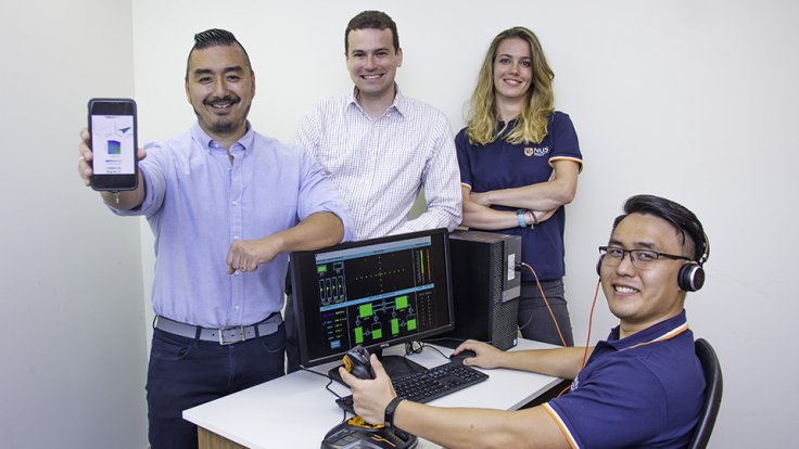 Prof Dean Ho (first from left) showing a schematic mobile version of CURATE.AI, while Mr Theodore Kee (seated) demonstrates the flight operations simulator software. With them are Asst Prof Christopher L. Asplund (second from left) and Dr Agata Blasiak (t