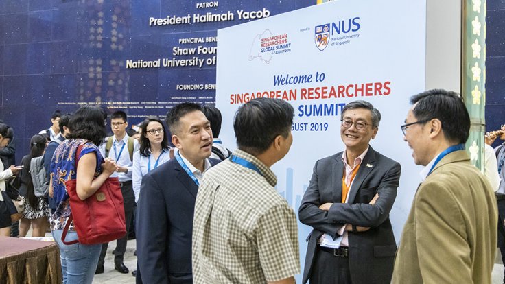 Prof Tan (2nd from right) speaking with Singaporean researchers between events at the Summit Prof Tan (2nd from right) speaking with Singaporean researchers between events at the Summit