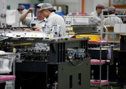 Employees are seen by their workstations at a printed circuit board assembly factory in Singapore 