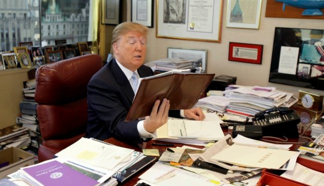 Donald Trump sifts through stacks of newspapers and printed articles to stay updated