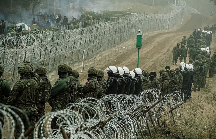 Polish soldiers and police watch migrants at the Poland/Belarus border near Kuznica, Poland Polish soldiers and police watch migrants at the Poland/Belarus border near Kuznica, Poland