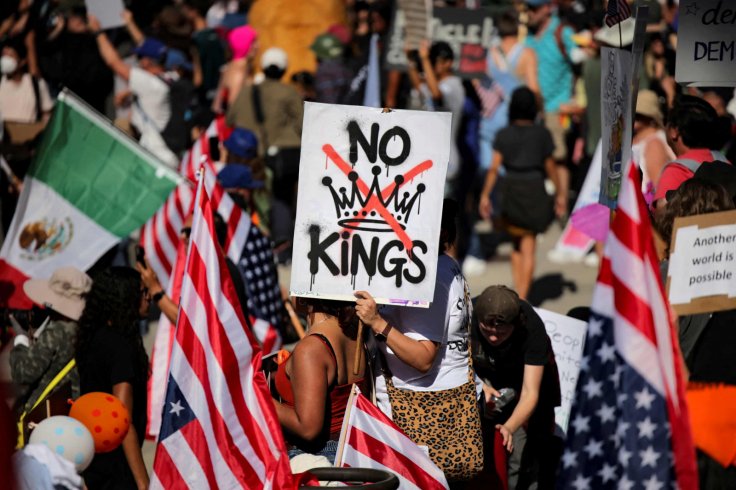 A protester holds a sign reading &ldquo;NO KINGS&rdquo; with a crown