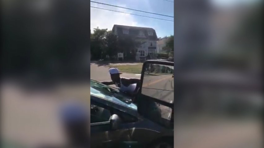 Woman clings onto car in bizarre traffic incident